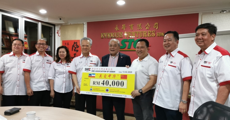 胡義基（左四）代表沙巴中小型企業公會移交4萬令吉關愛中華捐款，由吳添泉（右四）代表接收。