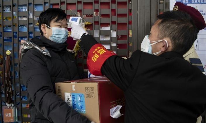 A security guard checks the temperature of a resident entering a compound in Hangzhou. AFP A security guard checks the temperature of a resident entering a compound in Hangzhou. AFP