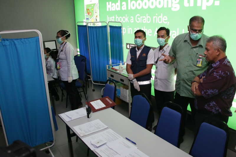 诺扎里（右）聆听卫生局官员讲解体温检测仪器的操作。