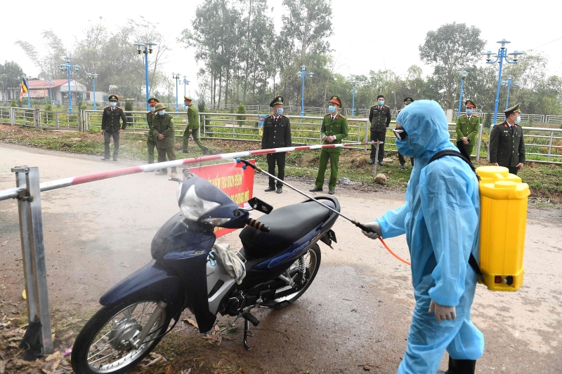 越南医护人员在山雷村一处检查站向一辆外来的摩哆车消毒。（图：法新社）