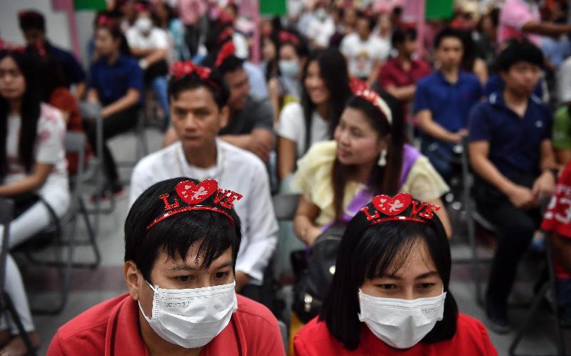 Thai couples in protective face masks wait to register their marriage licenses on Valentine's Day in Bang Rak, Bangkok's 