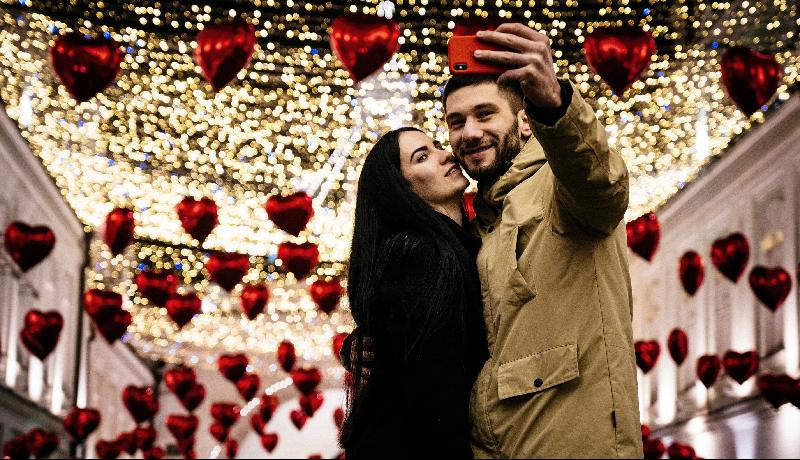 A couple poses for a selfie under heart-shaped balloons displayed for Valentine's Day in downtown Moscow. AFP