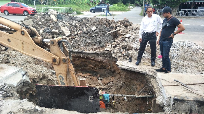 何桂文（左）向承包商员工了解修补地下大水管遇上的难度。