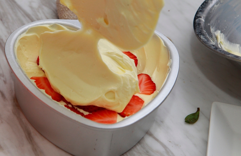 9.把一半奶油乳酪馅料放入有饼底的蛋糕模，在中层铺上切片草莓，再把剩余的奶油乳酪馅放入蛋糕模铺平，放入冰箱冷藏格一天。