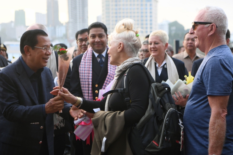 柬埔寨总理洪森（前左二）不但和船上的人握手，还送上玫瑰花束。（图：法新社）