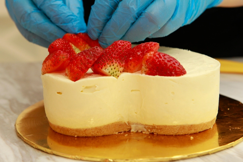 10.将芝士蛋糕脱模，把草莓切一半整齐的排在蛋糕上面，后再搽上水果胶及金箔点缀即可。