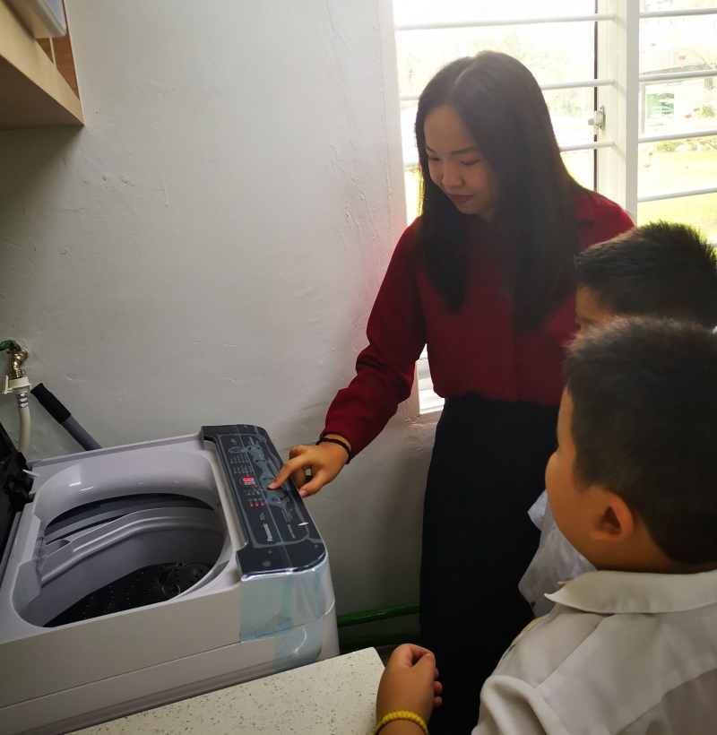 特殊班会更加注重教会学生生活技能。图为李盈璇老师教导学生如何使用洗衣机。