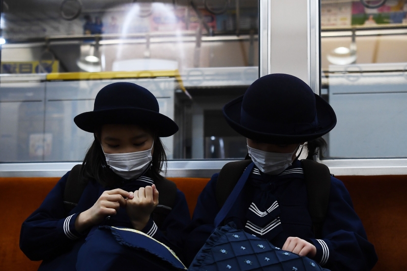 世卫组织呼吁日本坚持对抗新冠肺炎的努力。图为东京两名女生戴口罩搭地铁上学。（图：法新社）