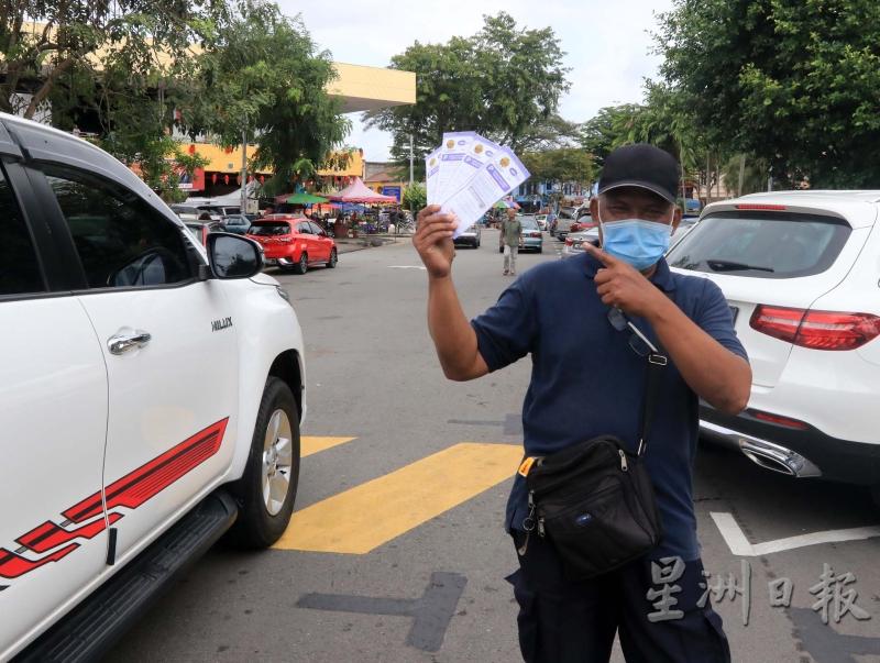 穿着印有巡查员制服的男子，在芙蓉公市入口处向驶入的车主售卖泊车固本。（图：星洲日报）