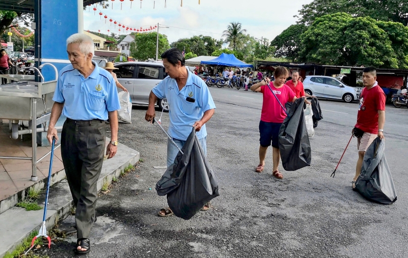 参与大扫除地民众分组在新村内四周捡拾垃圾，尤其要清理可能积水的器皿。
