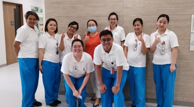 张女士（后排中）是新加坡第15名确诊病患，她昨日出院并与国家传染病中心医护人员合影。（张女士提供）