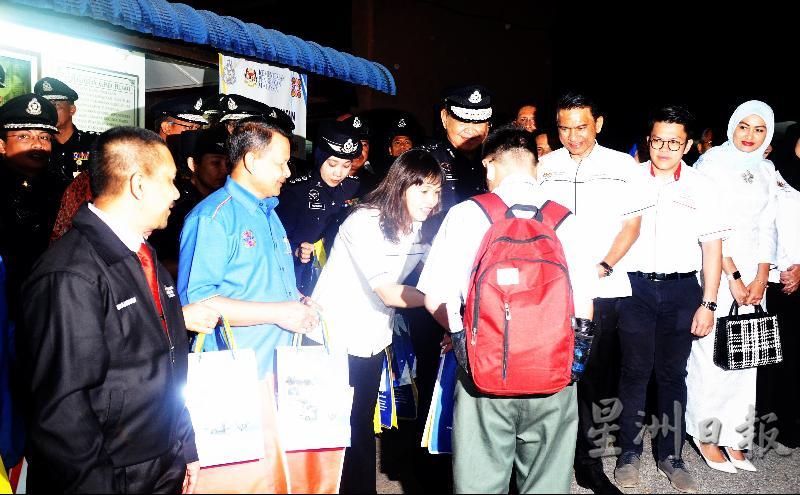 张念群（左三）和官员们在校门口派发礼袋给学生。