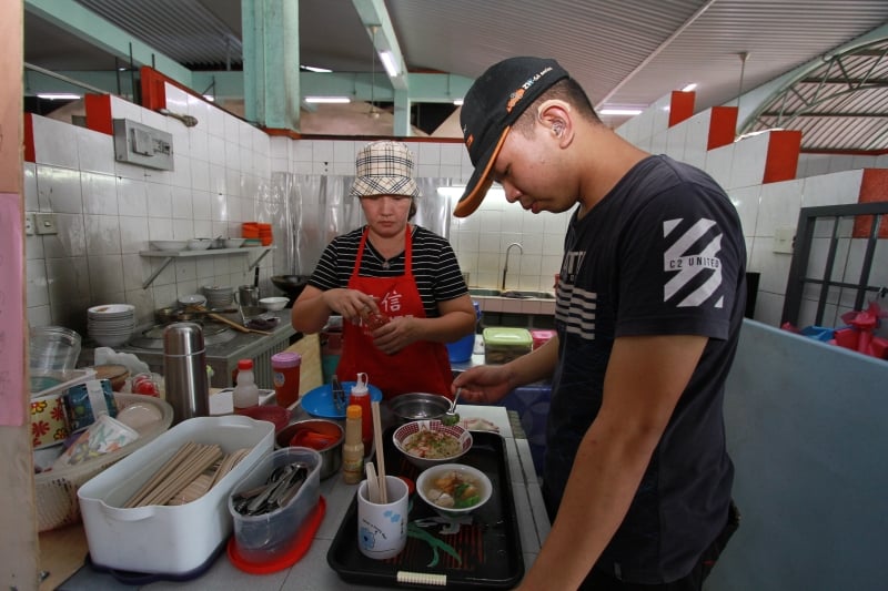 刘运鹉每天都陪在儿子身边，帮忙打理食摊生意，也充当儿子与顾客之间的沟通桥梁。