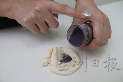 9.制作紫色“Love”：取少量面团，倒入少许甘薯紫粉，把它揉成条状，在刷了水在面团表层的情况下，将其摆成”Love“字眼。