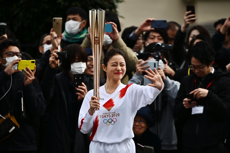 东京奥运会的火炬传递彩排在15日进行，但火炬手日本明星石原里美身后的人人一罩的画面，还是让人看了相当担忧东奥是否将如期进行。（图：法新社）