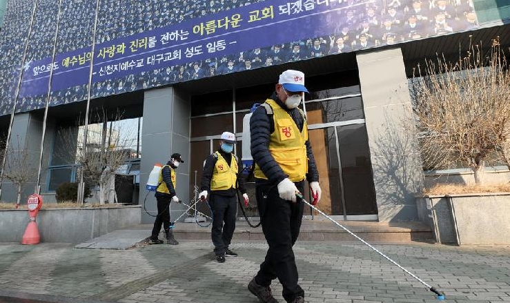 Health officials spray disinfectant in front of the Daegu branch of Shincheonji Church of Jesus. AFP