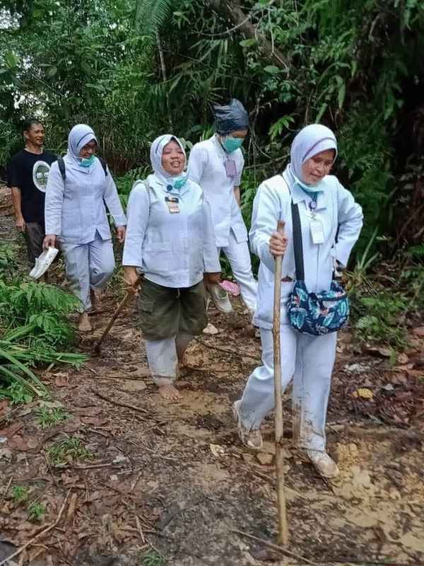 护士踩着泥泞湿滑的山路，双脚沾满泥巴，步行到哥打马鲁都偏远乡区为村民提供医疗服务。 