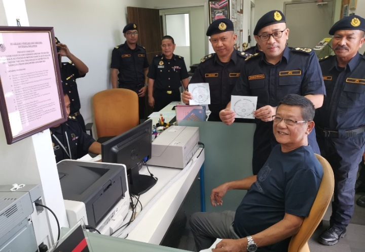 查马沙里（站者右二起）和吉打州陆路交通局局长伊斯马苏海米，展示其中一名泰国人获批准的国际通行许可证。