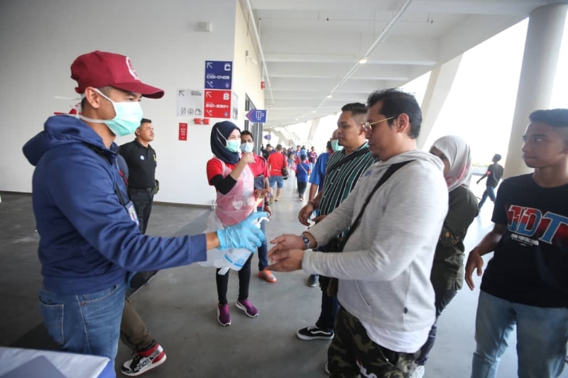 大会工作人员戴上口罩，为出席观礼的民众进行双手消毒和测量体温，作足防疫措施。