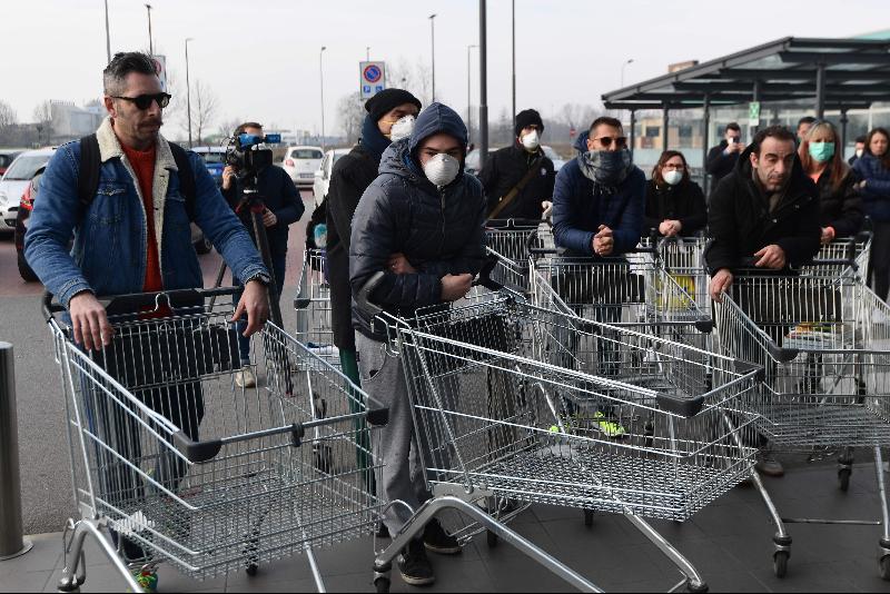 意大利爆发新型肺炎后，人心惶惶。在卡尔普斯特伦戈 小镇上，为免人群聚集，超市规定每次只准40人进入购物。图为民众在超市外排队，推着手推车准备进入，一些人戴上了口罩。（图：法新社）