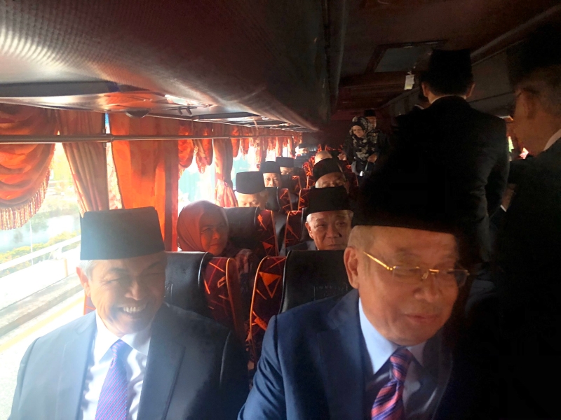 根据阿末马兹兰的推文，纳吉（右）和阿末扎希并列同坐，一起乘坐巴士到国家皇宫觐见国家元首。
