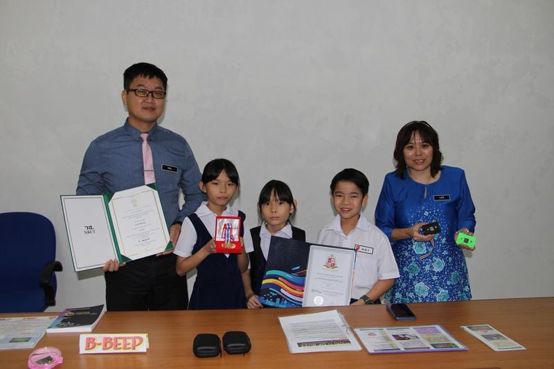 开明小学校长夏正恒（左）、副校长李晓娟（右）与参赛的3名学生（左一林君茹、林妍茹、林奕宁）展示获奖的设备与奖状。