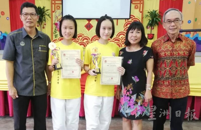 郑家欣和郑嘉媛姐妹获得佳作奖后展示奖杯及奖状。右二是赖安雅老师。
