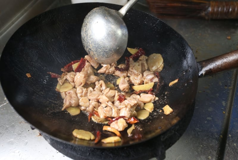将蒜米、辣椒乾、姜片爆香，并将腌好的鸡肉沥乾，入锅翻炒至25%熟。