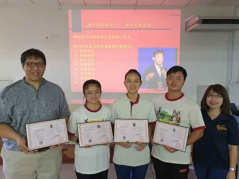 考获“中国民族乐器演奏艺术水平考级”的团员领取证书后与江赐良（左）及温慧慈（右）合影。