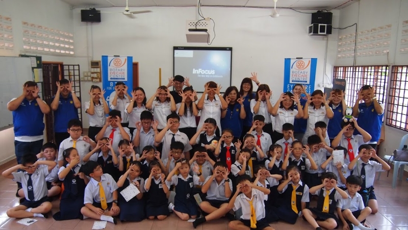峇株巴辖扶轮社护眼中心组员到巴力双倪新华学校，为学生免费验眼及举行讲座会后，与该校师生开心合影。
