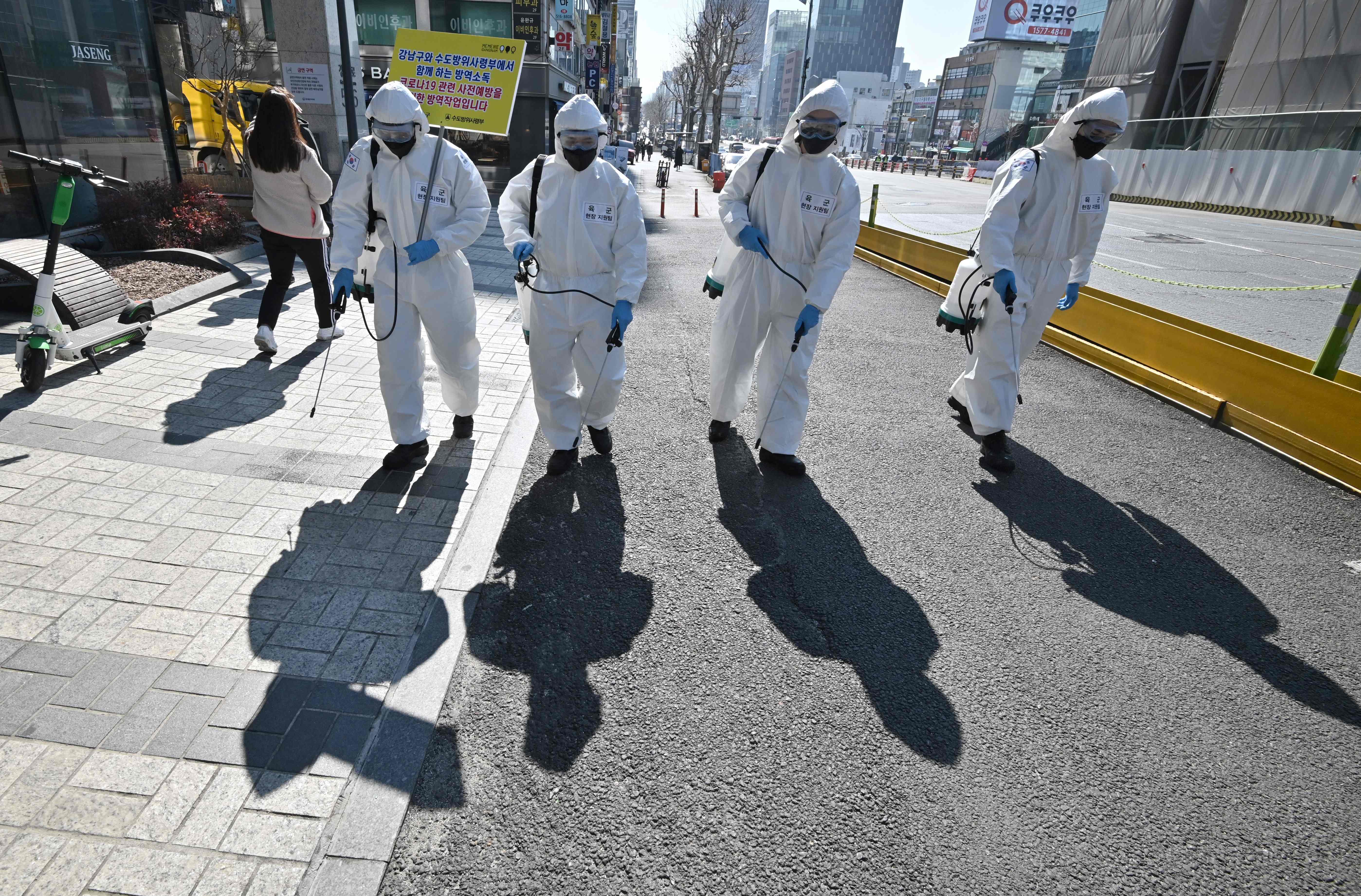 穿着防护衣的韩国军人在街上消毒，期盼防止疫情再度扩散。（法新社照片）