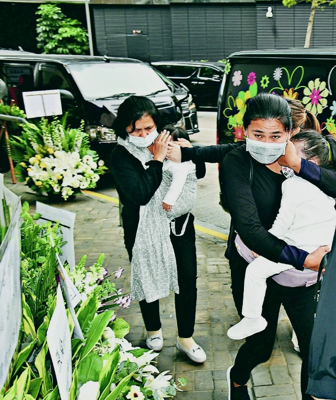 郭富城两名年幼女儿由外佣抱着前往灵堂，并警觉地用手遮掩她们容貌。（图取自互联网）