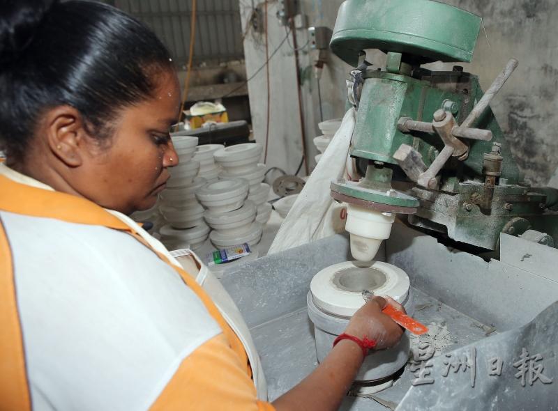 制胚分注浆和挤压方式，女工用机器压出茶杯。