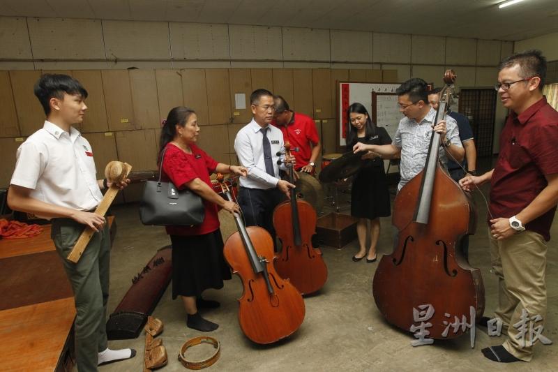 华乐团所使用的乐器许多已经损坏不堪。图为加影育华文化体育理事会理事们向本报记者展示严重损坏的大小提琴和大钹。