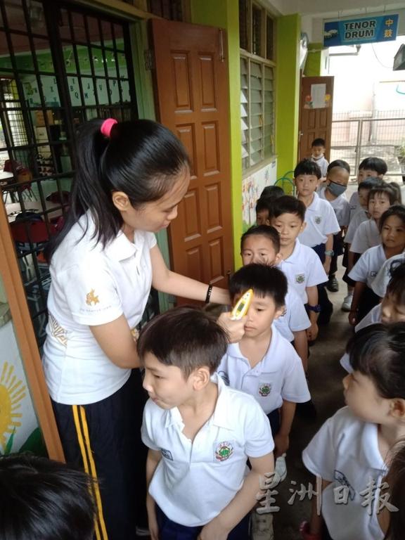 关丹培才华小的教师为学生测量体温。