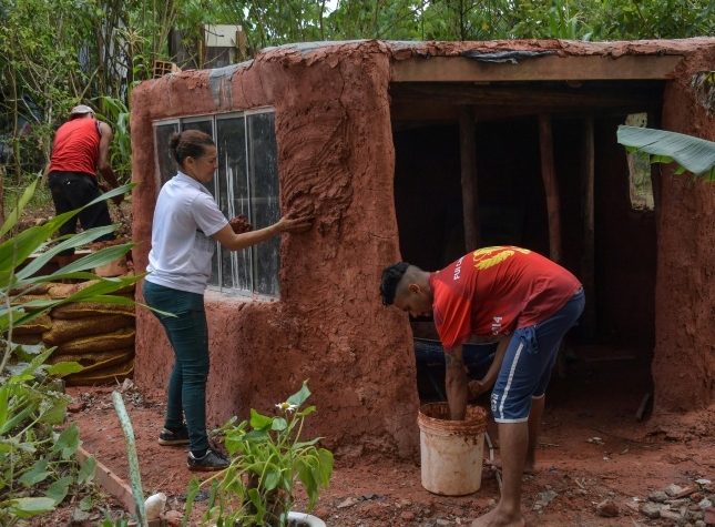 Community leader Lia de Souza (C) and two residents build a house with clay in the Vila Nova Esperanca. AFP