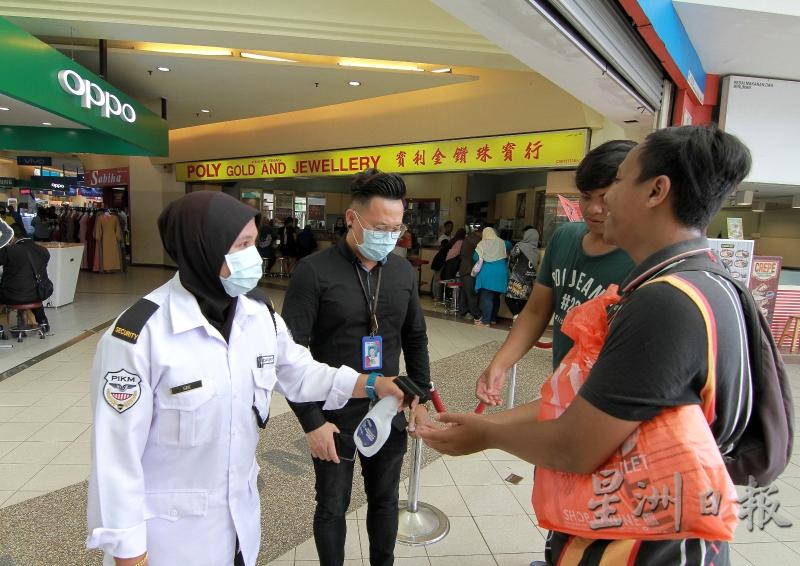 关丹百利广场保安人员为每一位进入商场的顾客喷洒消毒搓手液，降低感染风险。 （图：星洲日报）