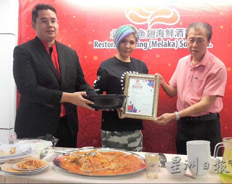 北京楼鱼翅海鲜酒家经理林亚来(右起)颁发奖状给汤美凤,证明完成10.6公斤挑战。左为大好运酒家及北京楼鱼翅海鲜酒家发言人李文晖。