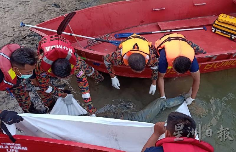 搜救人人员合力把搁在沿河泥沼处的遗体搬运上船。