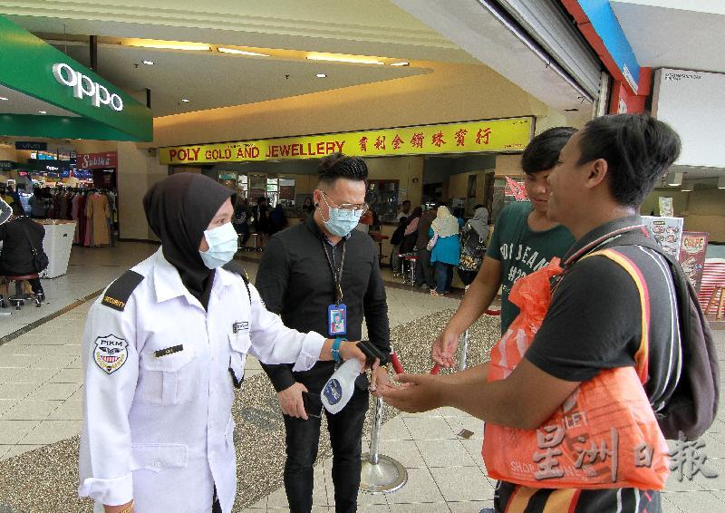 关丹百利广场保安人员为每一位进入商场的顾客喷洒消毒搓手液，降低感染风险。