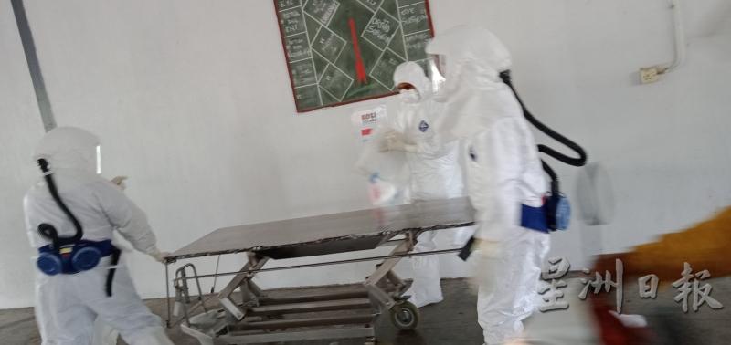 全副武装的医务人员，昨日下午登上砂中央医院病房，把冠病死亡病例死者的遗体移到停尸间。