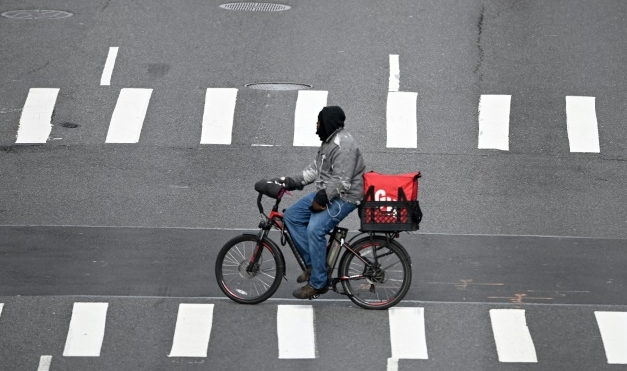 A food delivery man crosses 1st Avenue in Manhattan on March 17, 2020 in New York City. AFP