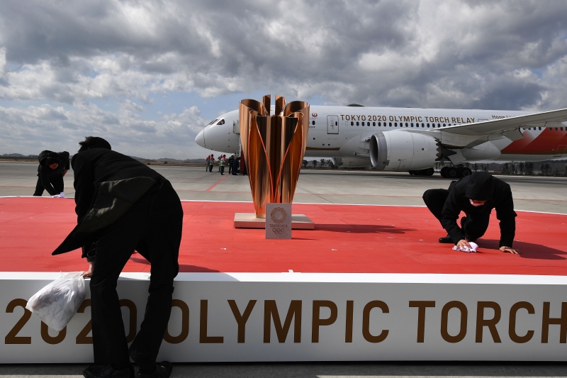 东京奥运会火炬已经抵达了日本宫城县的航空自卫队松岛基地，不日就会展开全国传递活动，图为工作人员在打扫清理摆放火炬的小舞台。（图：法新社）