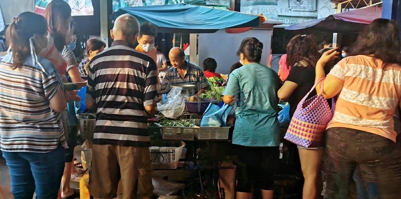 许多民众聚集在菜摊选购，有些民众及小贩甚至没戴口罩。
