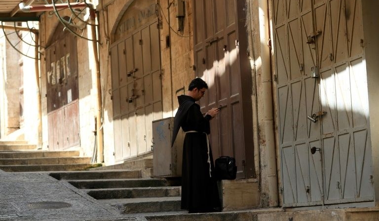 A Fransiscan friar stops in front of closed shops in the Old City of Jerusalem. AFP