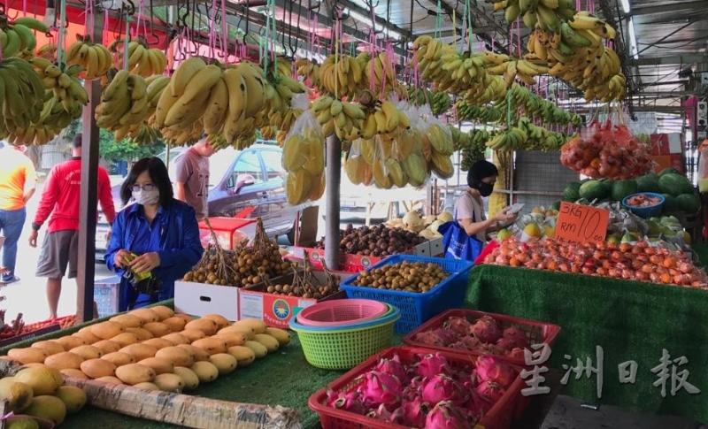 不少顾客前来水果摊位选购水果。