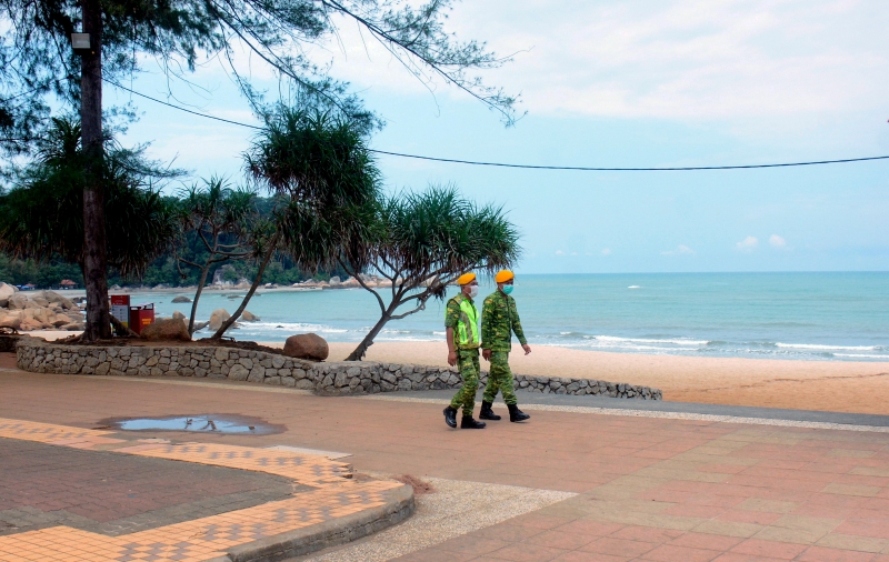 两名志愿警卫队成员在直落尖不辣海滩巡逻，四周不见人潮。