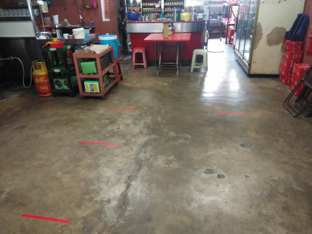 咖啡店小贩在地上用红黄贴纸做记号，划分1公尺距离，让顾问等候买食物。