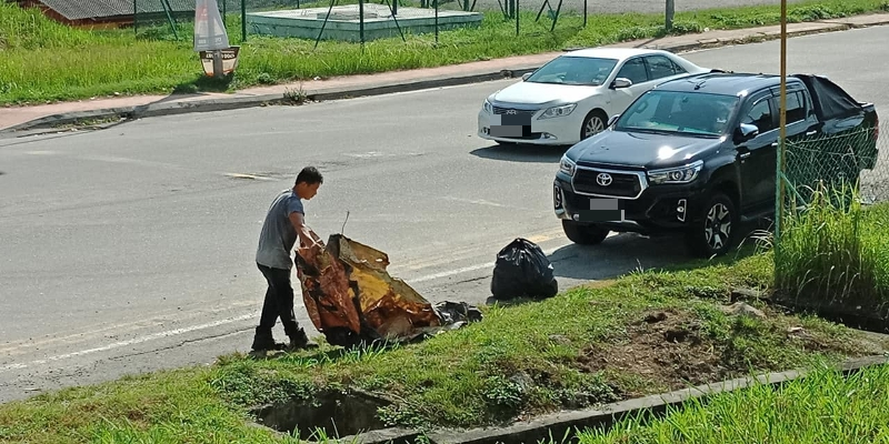 男子一路沿着街道边缘捡完垃圾后，便将垃圾打包放进车子的后车厢里