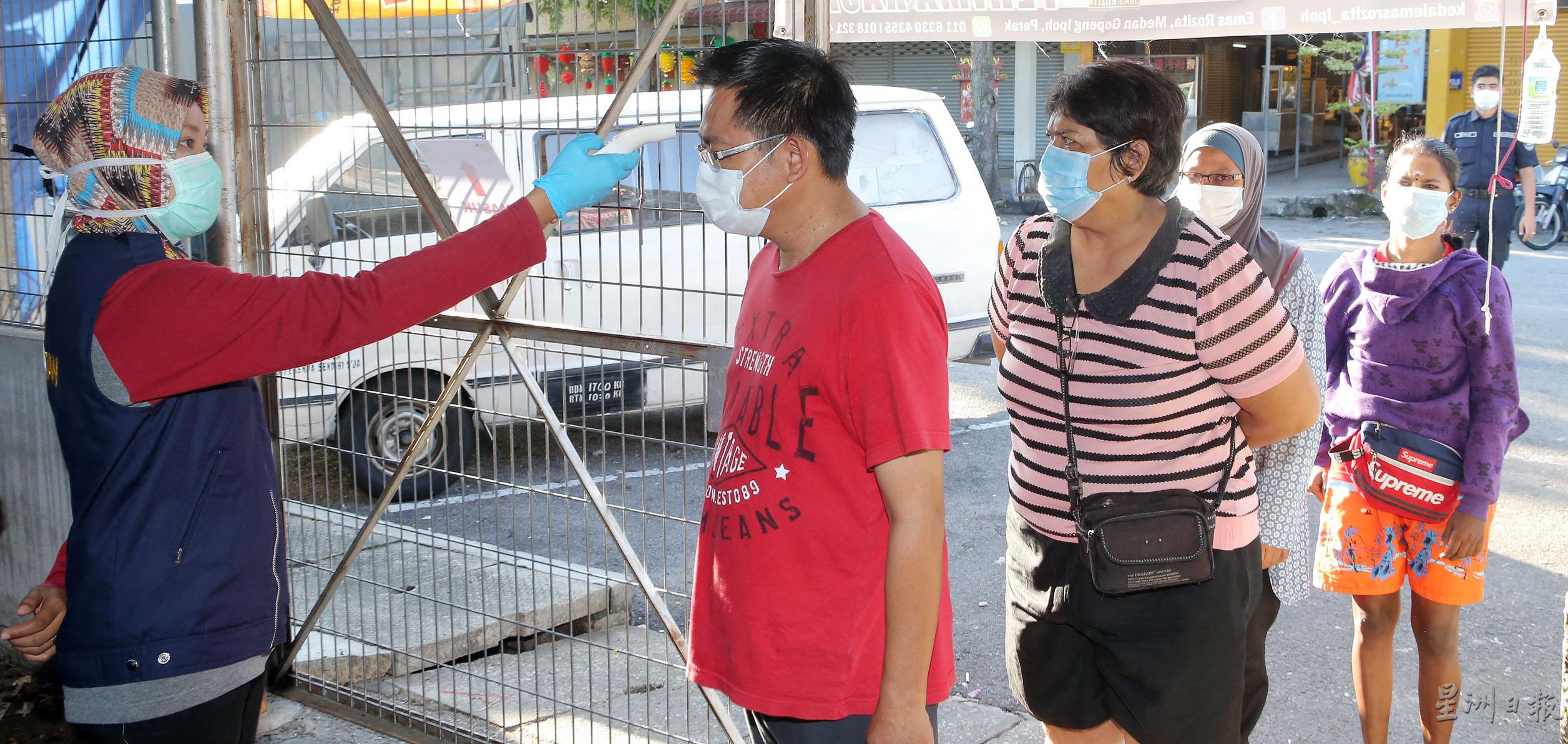 怡保市政厅官员为进入巴刹的民众测量体温。

